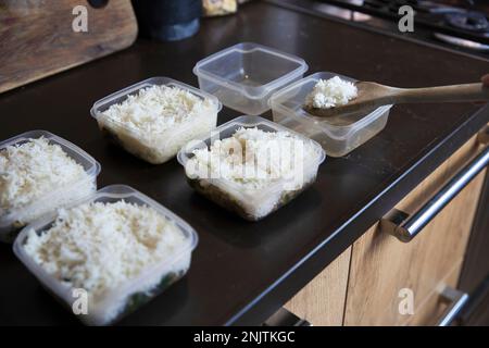 Preparazione dei pasti. Impilare le cene di riso e pollo cucinate in casa in contenitori pronti per essere congelati per un uso successivo come pasti pronti veloci e facili. Preparazione del cibo Foto Stock