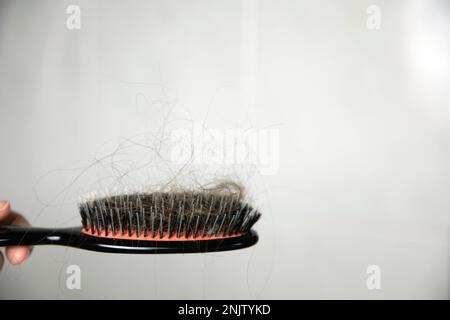 Problema di perdita dei capelli, periodo postpartum, disturbi mestruali o endocrini, squilibrio ormonale, concetto di stress. Molti capelli cadono dopo la pettinatura con la spazzola per capelli Foto Stock