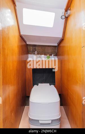 Bagno accogliente in piccolo yacht con pareti in legno. Compatto, elegante e moderno yacht pensieroso. Concetto di condizioni confortevoli durante il viaggio. Foto Stock