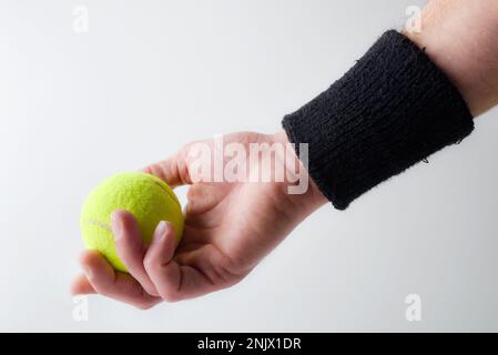 Sfondo con mano con braccialetto nero cattura palla da tennis su sfondo isolato chiaro. Vista frontale. Foto Stock
