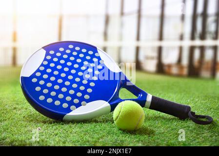 Racchetta e palla di padel sul pavimento in erba artificiale nel campo all'aperto. Vista frontale. Foto Stock