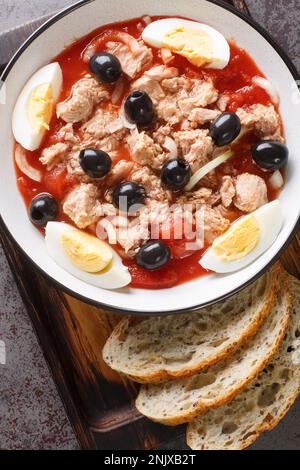 Insalata di Murcian o mojete, una ricetta tradizionale fresca e leggera che viene preparata con pomodoro, tonno in scatola, olive nere, uovo e cipolla closeup sul pla Foto Stock