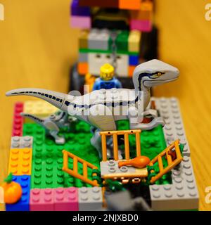 Un dinosauro giocattolo posto su un tavolo di legno accanto a colorati mattoni Lego e blocchi Foto Stock