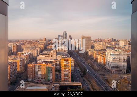 Pittoresca vista di case residenziali a più piani situato in centro con strada asfaltata contro il cielo nuvoloso a Madrid Foto Stock
