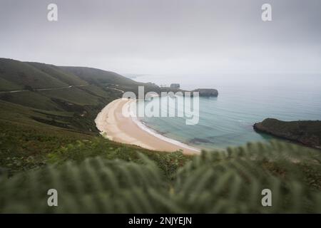 Incredibile vista di mare ondulato senza fine spiaggia sabbiosa vicino alle verdi colline in giornata di mare nelle Asturie Foto Stock