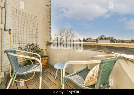 Sedie verdi in vimini poste sul balcone senza finestre con tavolino rotondo vicino alle piante in vaso nelle giornate di sole Foto Stock