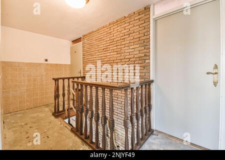 Design interno della casa in stile tradizionale di scale con ringhiera in legno vicino alle porte e muro di mattoni con pavimento in cemento Foto Stock