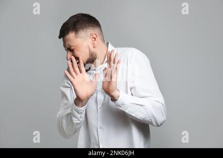 Ritratto dell'uomo che sente paura su sfondo grigio Foto Stock