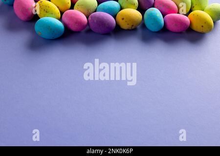 Immagine di uova di pasqua multicolore con spazio copia su sfondo viola Foto Stock