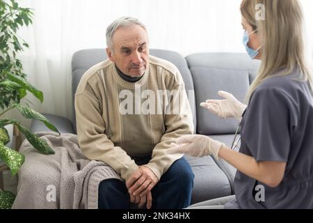 Turbato l'uomo più anziano ascoltando il discorso di sostegno di una piacevole dottoressa, la testa ha sparato in primo piano. Specialista medico di mezza età vecchio paziente maschio Foto Stock