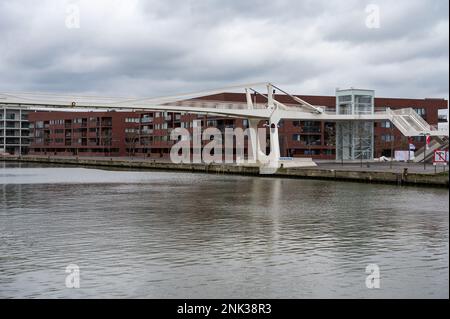 Vilvoorde, Regione del Brabante Fiammingo - Belgio - 19 2023 febbraio - piccolo ponte pedonale sul canale con condomini contemporanei nel retro Foto Stock