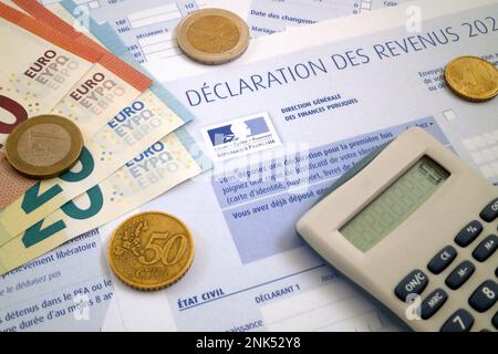 Una calcolatrice e alcune monete e banconote in euro in cima ad un modulo francese di imposta sul reddito. Foto Stock