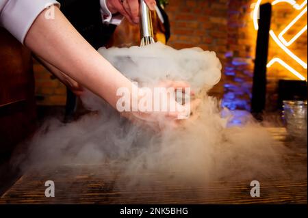 preparazione del gelato con le mani femminili dell'azoto liquido che tengono una ciotola nei fumi Foto Stock