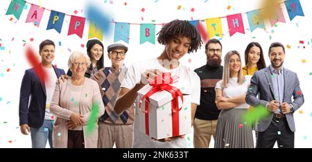 Felice giovane afroamericano che apre un regalo e la gente si è riunita dietro ad una festa a sorpresa isolata su sfondo bianco Foto Stock