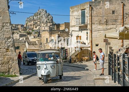 I turisti in tuk-tuk visitano il complesso dei Sassi di Matera di abitazioni rupestri nell'antica città di Matera, capitale della Basilicata, Italia Meridionale Foto Stock