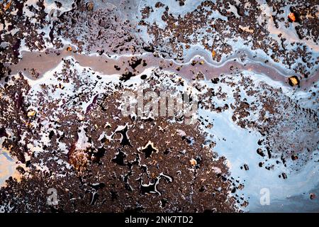 Fuoriuscita di benzina sull'asfalto con una striscia divisoria bianca in un parcheggio come una texture o sfondo. Foto Stock