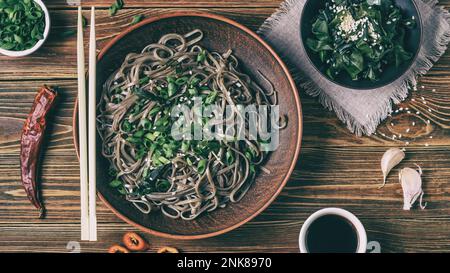 Ancora vita con vista dall'alto dei tradizionali noodle di soba giapponesi con nori (alghe commestibili) e salsa di soia, su un guardaroba di superficie di legno Foto Stock