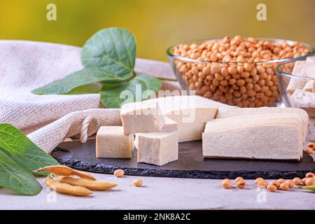 Il tofu, noto anche come cagliata di fagioli, ha tagliato sulla superficie nera della pietra ardesia, closeup con fuoco selettivo Foto Stock