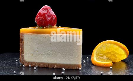 dessert cheesecake con gelatina d'arancia e fragole, su sfondo nero Foto Stock