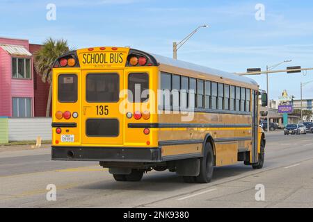 Galveston, Texas - 2023 febbraio: Vista posteriore di un scuolabus che guida lungo la strada sul lungomare Foto Stock
