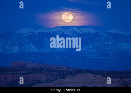 Luna piena che si innalza sulle montagne la SAL innevate al crepuscolo serale vicino a Moab, Utah. Foto Stock