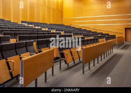 All'interno di una grande sala conferenze piena di sedie grigie pieghevoli e pareti in legno Foto Stock