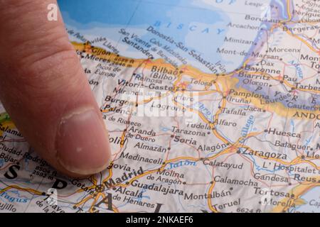 Primo piano della mappa colorata con il dito che punta a Madrid, Spagna, messa a fuoco selettiva, profondità di campo ridotta, sfocatura dello sfondo Foto Stock