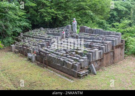 Statue di pietra di Ojizou san, protettore dei bambini e protettore dei viaggiatori, e tombe Giappone. Foto Stock