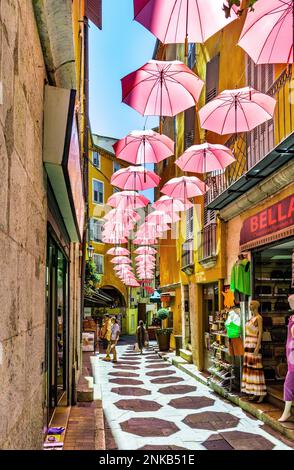 Grasse, Francia - 6 agosto 2022: Case storiche e strade strette decorate con ombrelloni rosa del centro storico della città di profumeria di Gr Foto Stock