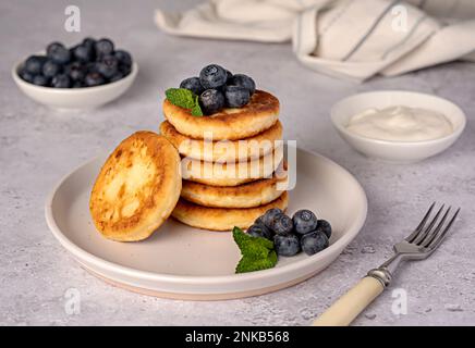 Fotografia alimentare di pancake, formaggio di ricotta, mirtilli, crema, colazione; brunch, menta, mattina Foto Stock