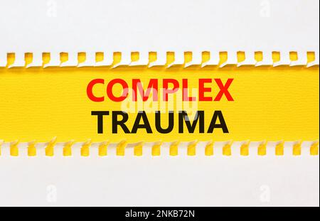 Simbolo di trauma complesso. Concetto parole trauma complesso su carta gialla. Bellissimo sfondo bianco tavolo giallo. Psicologia aziendale trauma complesso conce Foto Stock