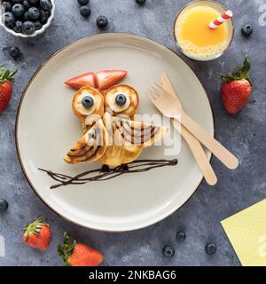 Frittelle fatte in casa a forma di gufo servite con frutta e succo di frutta. Foto Stock