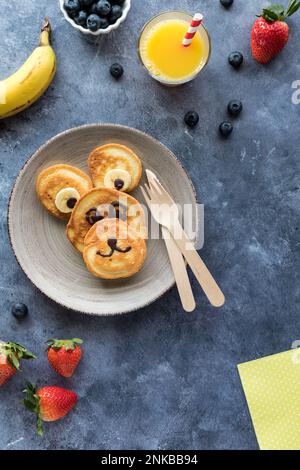 Frittelle fatte in casa a forma di orso, servite con frutta e succo di frutta. Foto Stock