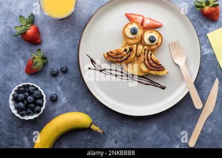 Frittelle fatte in casa a forma di gufo, servite con frutta e succo di frutta. Foto Stock