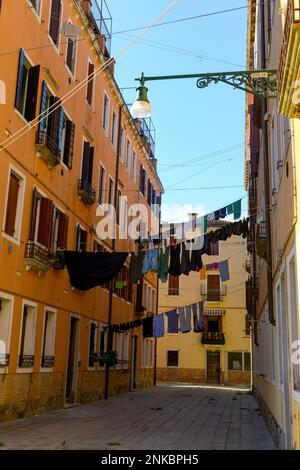 Tipico angolo della città con antichi edifici colorati asciugare i vestiti su una linea di abbigliamento all'aperto nelle giornate di sole. Venezia, Italia Foto Stock