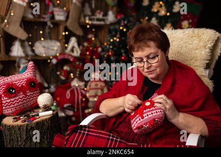 La nonna scaglia un gufo peluche nella disposizione di Natale. In studio Foto Stock