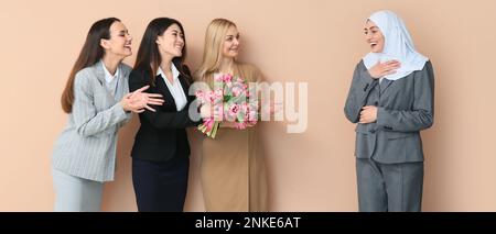 Belle donne salutano il loro collega musulmano con fiori di tulipano su sfondo beige. Celebrazione della Giornata internazionale della donna Foto Stock