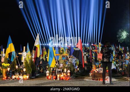 Lviv, Ucraina. 23rd Feb, 2023. La donna visita le tombe dei soldati caduti nel campo del cimitero di Lychakiv, dove centinaia di soldati ucraini morti l'anno scorso sono sepolti durante un evento di commemorazione come simbolico 'raggi di memoria' sono stati illuminati nel cimitero militare di Lychakiv per celebrare il primo anniversario di La guerra della Russia contro l'Ucraina. La Russia ha invaso l'Ucraina il 24 febbraio 2022, scatenando il più grande attacco militare in Europa dalla seconda guerra mondiale Credit: SOPA Images Limited/Alamy Live News Foto Stock