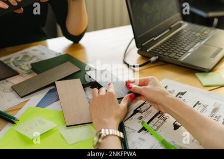 Primo piano di due architetti con campioni, BluePrint e laptop sul tavolo in ufficio Foto Stock
