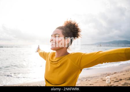 Donna spensierata con braccia tese in piedi in spiaggia Foto Stock