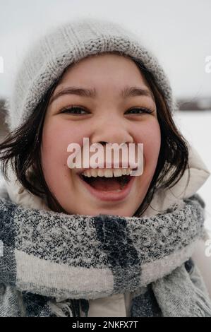 Allegra ragazza adolescente che indossa un cappello a maglia e una sciarpa Foto Stock