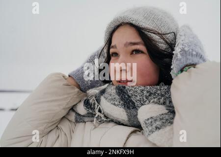 Ragazza teenage premurosa che indossa cappello e sciarpa in maglia in inverno Foto Stock