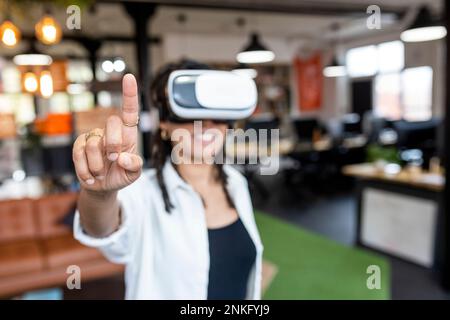 Donna d'affari che indossa occhiali VR rivolti in ufficio Foto Stock