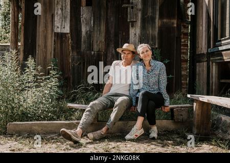 Coppia seduta su panca di fronte al fienile Foto Stock