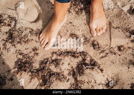 Donna in piedi nudi sulla sabbia in spiaggia Foto Stock