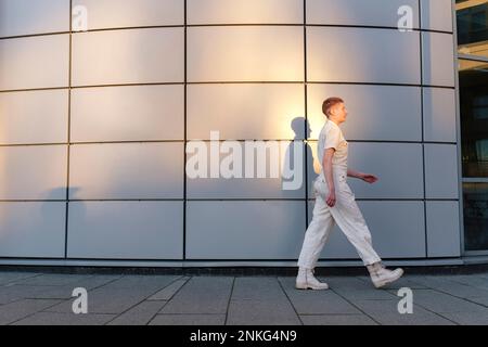 Persona non binaria che cammina di fronte all'edificio Foto Stock