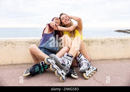 Amici allegri che si divertono seduti sul lungomare Foto Stock