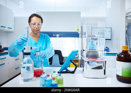 Scienziato femminile che mescola liquidi in un laboratorio microbiologico Foto Stock