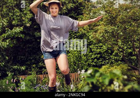 Giovane donna eccitata che salta nel cortile posteriore Foto Stock