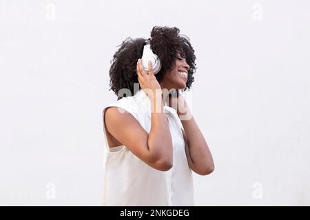 Una donna felice che indossa le cuffie ama ascoltare la musica su sfondo bianco Foto Stock